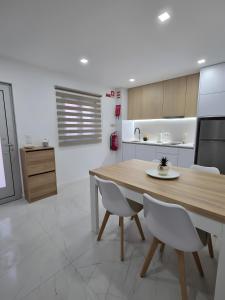 a kitchen with a wooden table and white chairs at Casa da Lota in Vieira de Leiria