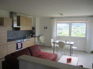 a living room with a couch and a table and a kitchen at Ferienwohnungen Tollhof - Near Bolzano and castles, with a guest card for families and couples, offering panoramic views in Cornaiano