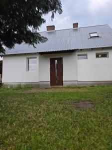 a white house with a brown door and a yard at Apartament 1 w Leśnym Zaciszu in Czertyń +4 photos