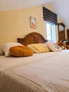 a bedroom with two beds with pillows and a window at Apartamento Duplex con jardín A Casiña de Divina in Lago