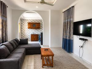 a living room with a couch and a flat screen tv at Peace apartment in Brufut