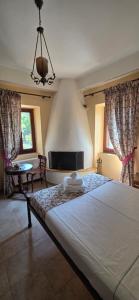 a bedroom with a bed and a table and windows at Triantafillies Traditional Hotel in Portaria