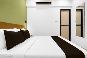a white bed with black pillows in a bedroom at Super Collection O MIDC Mahape Mumbai Formerly Hotel Didar House in Mumbai +54 photos
