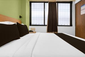 a large white bed in a room with two windows at Super Collection O MIDC Mahape Mumbai Formerly Hotel Didar House in Mumbai