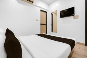 a bedroom with a white bed with a television on the wall at Super Collection O MIDC Mahape Mumbai Formerly Hotel Didar House in Mumbai