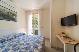 a bedroom with a bed and a desk and a television at Residence Hotel Villa Mare in Portoferraio