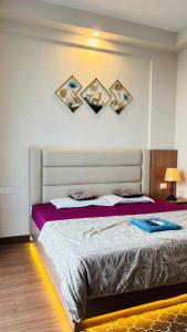 a bedroom with a large bed with paintings on the wall at Skybloom stays in Greater Noida