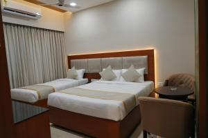 a hotel room with two beds and a table at EMBASSY PARK - Near US consulate, Apollo hospital, Sankaranethralaya in Chennai