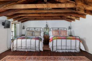 two beds in a room with wooden floors at Historic Rumpel Kammer - Compound in Fredericksburg
