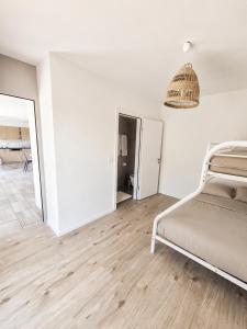 a white bedroom with a bed and a hallway at La maison IDEL in Yvonand