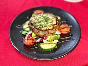 a black plate of food with a steak and vegetables at Cross Keys Hotel Chatteris in Chatteris