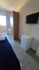 a bedroom with a bed and a flat screen tv at Lagoa Suítes in Lagoa Santa