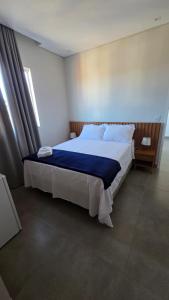 a bedroom with a large bed with a blue blanket at Lagoa Suítes in Lagoa Santa