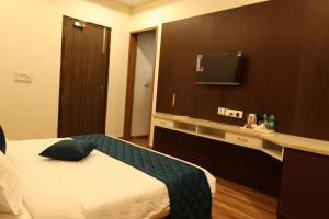 a hotel room with a bed and a tv at Skvr Grand in Theni +7 photos