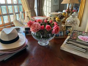 a vase of roses sitting on a table with a hat at Rose Cottage De Hoop Farm PAARL SOUTH in Hartebeeskraal
