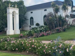 a white house with a garden of flowers at Rose Cottage De Hoop Farm PAARL SOUTH in Hartebeeskraal