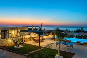 an outdoor patio with tables and umbrellas at dusk at Nysa Luxury villas 3-4-5-6 in Heraklion