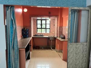 an orange bathroom with a sink and a window at Peaceful Living in Kolkata