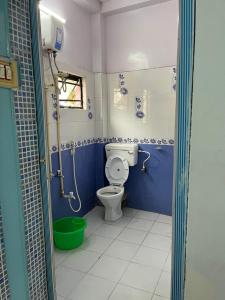 a bathroom with a toilet and a green bucket at Peaceful Living in Kolkata
