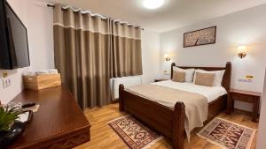 ein Schlafzimmer mit Bett, Schreibtisch und Fernseher in der Unterkunft Pensiunea ROCA Maramures in Deseşti + 65 Fotos