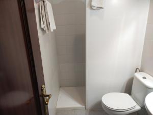 a white bathroom with a toilet and a shower at Hostal El Polígono in Lucena