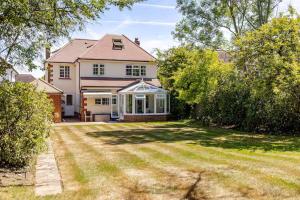 a large white house with a yard with trees at Leafy Suburban Bed and Breakfast in Northwood