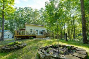 a home in the woods with a large deck at Private Dock & Deck: Tranquil Dam Pond Cottage! in Augusta