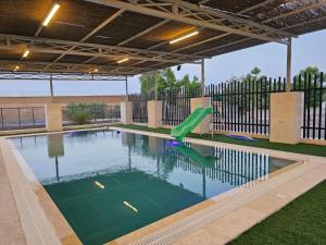 a swimming pool with a slide in the water at مزرعه فلج فارم Falaj-farm in Falaj al Mu‘allá
