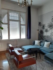 a living room with a blue couch and chairs at The Stage Door Apartment in Debrecen