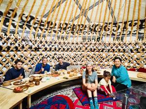 a group of people sitting around a table in a boat at Azem Guest House in Kasymbek