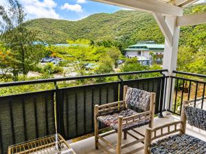 a porch with two chairs and mountains in the background at Kalista - Studio Luxueux - Anse Marcel in Saint Martin