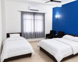 a bedroom with two beds and a blue wall at Niru Buddha Hotel, Lumbini in Rummindei