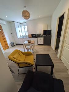 a living room with a yellow couch and a table at Appartement La Jungle in Villebois +12 photos