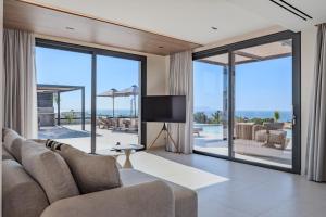 a living room with a couch and a tv and sliding glass doors at Nysa Luxury villas 3-4-5-6 in Heraklion