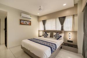 a bedroom with a large bed with blue and white pillows at Hotel Lavish Regency in Ahmedabad +6 photos