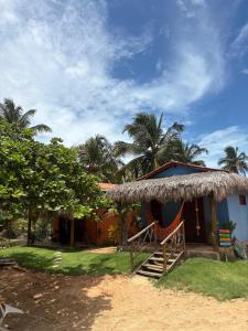 a small house with a straw roof and palm trees at Point lanabarra in Amontada