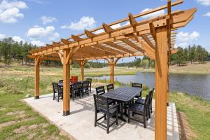 a wooden pergola with tables and chairs next to a lake at Pondside Lodge BHBungalows #5 in Custer