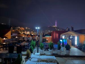 a rooftop patio with tables and chairs at night at Mit Hotel Tbilisi in Tbilisi City