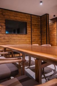 a large wooden table with chairs and a tv on a wall at The Frame Croatia in Ravna Gora