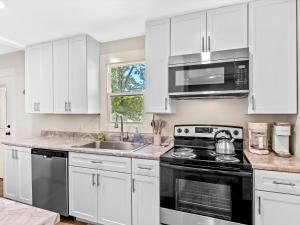 a kitchen with white cabinets and a stove top oven at Modern Coastal Cottage Near Destin & Beaches in Niceville