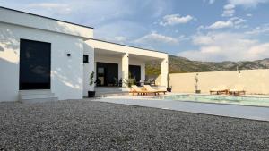 a white house with a swimming pool and a patio at Villa Maja in Blagaj