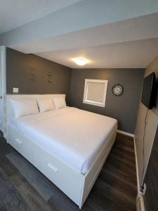 a bedroom with a white bed and a clock on the wall at 94 Motel & RV Park in One Hundred Mile House