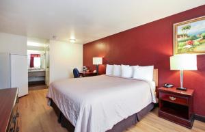 a hotel room with a large bed with a red wall at Red Roof Inn Lompoc in Lompoc