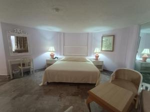 ein Schlafzimmer mit einem Bett und zwei Stühlen und zwei Lampen in der Unterkunft Hotel Acapulco Malibu in Acapulco