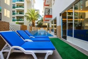 a patio with blue lounge chairs and a swimming pool at Dublin Hotel in Alanya