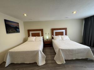 ein Hotelzimmer mit zwei Betten mit weißer Bettwäsche in der Unterkunft Hotel Finisterre in Mexiko-Stadt