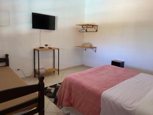 a bedroom with a bed and a flat screen tv at Pousada casa amarela Analândia SP in Analândia
