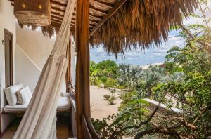 a room with a hammock and a view of the beach at Villa Alegria - La Villa Group in Jericoacoara