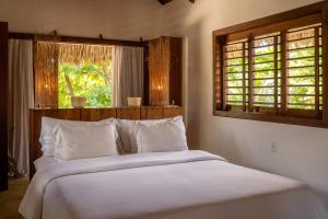 a bedroom with a bed with white sheets and a window at Villa Alegria - La Villa Group in Jericoacoara +98 photos
