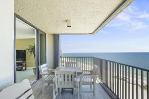 a dining table and chairs on a balcony with the ocean at Two Bedroom Corner Condo with Panoramic Gulf Views in Clearwater Beach